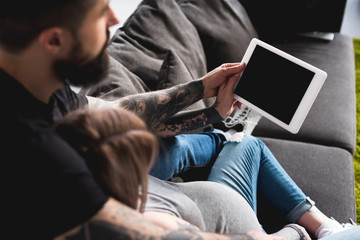 pregnant girlfriend looking at tablet with boyfriend at home
