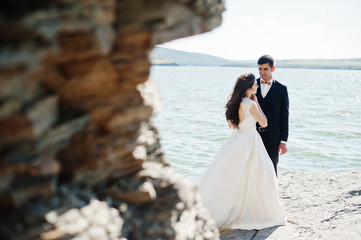Wedding couple at breathtaking landscape with rock and lake.