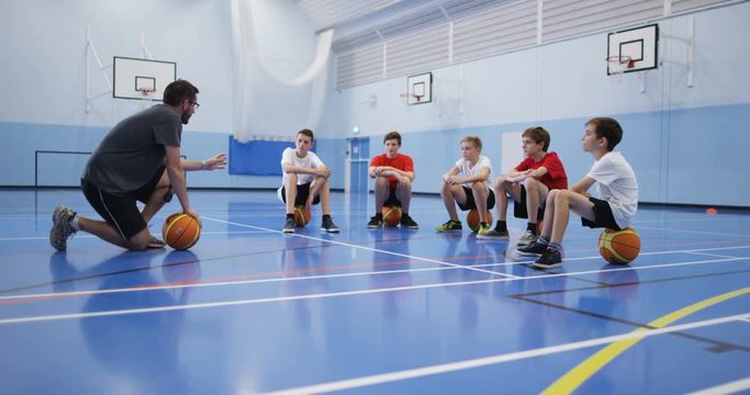 4k, A male coach talking to a group of teenage boys during a physical education class.