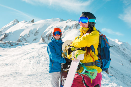 Photo of sportive man and woman with snowboard against background of snowy hills