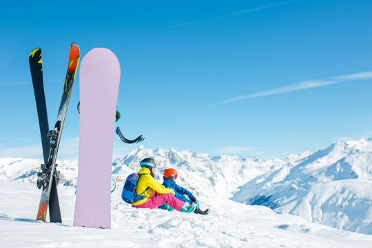 Image of snowboard, ski on background of sitting sports couple on snowy hill in winter afternoon