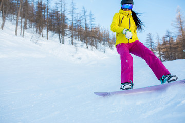 Photo of athlete girl wearing helmet and mask snowboarding from snowy slope with trees