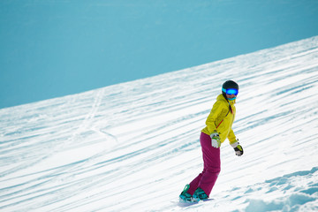 Photo of sports woman wearing ahelmet and mask, snowboarding from mountain slope