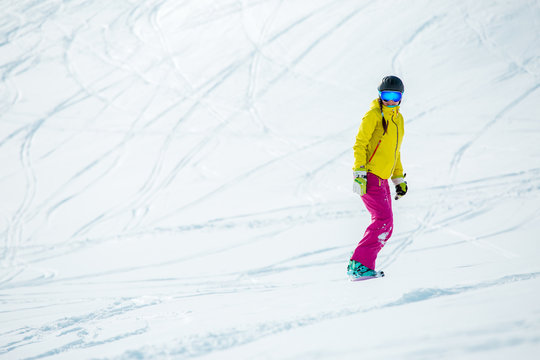Image of woman wearing helmet in sports clothes snowboarding