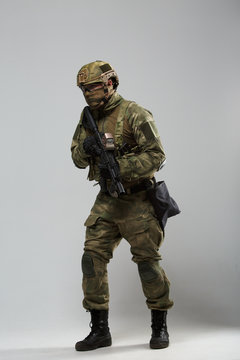 Full-length image of military man in camouflage with gun