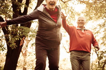 Seniors couple in sports clothing playing and catching in park.
