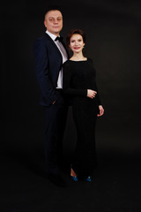 Elegance woman in black evening dress with man in suit posed on studio isolated on black. Duet couple of two.