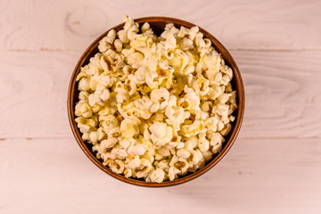 Ceramic bowl with popcorn on wooden table. Top view