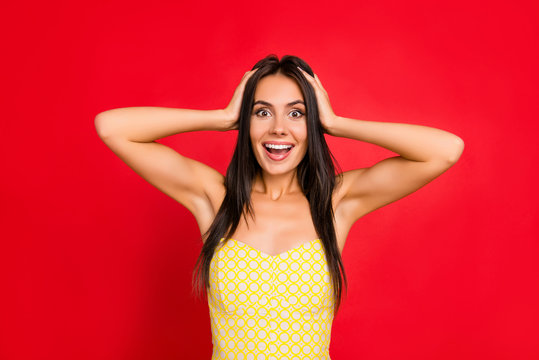 Portrait of cheerful, surprised, astonished, trendy, brunette girl touching head with two hands having open mouth, unexpected, unbelievable expression, isolated on red background