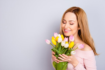 Obraz na płótnie Canvas Motherhood international closed eyes freshness romance concept. Close up portrait of beautiful lovely cute woman with toothy smile smelling the tulips in hands isolated on gray background copy-space