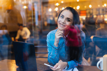 outside the window a happy woman is sitting and holding the phone in her hands