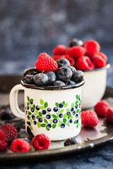 Fresh ripe blueberry and raspberry in mugs