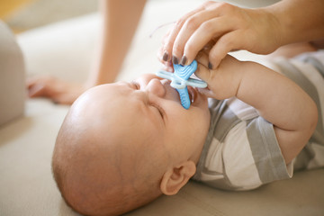 Crying little baby boy at home with mother. Close up.