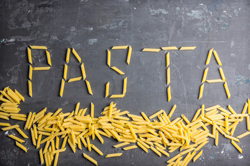 Raw pasta on the rustic wooden background. Selective focus. 
