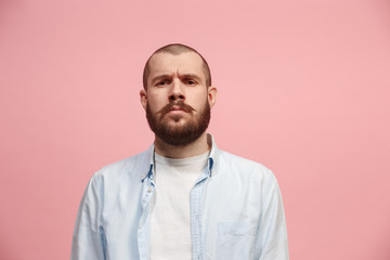 Obraz premium The serious businessman standing and looking at camera against pink background.