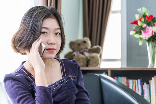 Young asian woman short hair use mobile phone in living room