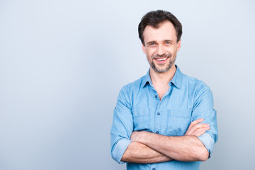 Portrait of confident concentrated cheerful excited glad with shiny beaming smile wearing light blue jeans shirt with rolled-up sleeves standing with folded arms isolated on gray background copyspace