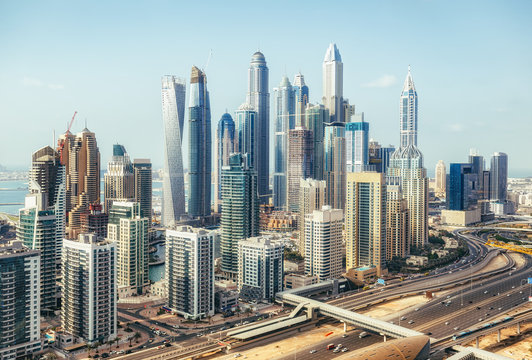Scenic panoramic view of modern city architecture. Aerial daytime skyline of Dubai Marina, UAE, with skyscrapers and highways. Summer travel background.