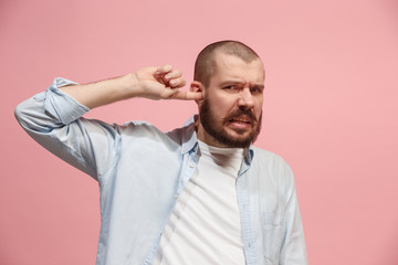 Obraz premium The Ear ache. The sad man with headache or pain on a pink studio background.