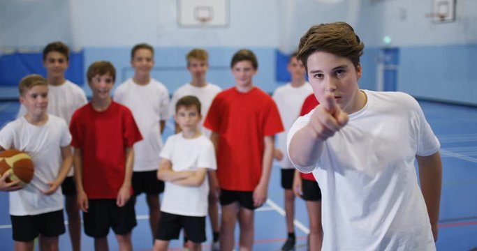 4k, Portrait of a cheerful smiling basketball player holding out finger on court indoors. Slow motion.