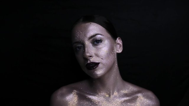 The girl's face is covered with gloss and glitter . Posing