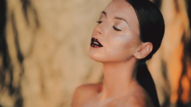 The girl's face is covered with gloss and glitter . Posing