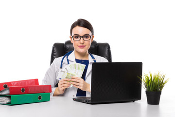 Young woman doctor with stethoscope sitting on the desk at medical office in white uniform on white background