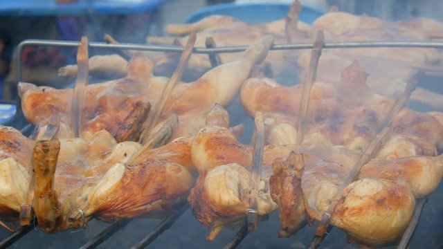 Whole chicken carcass grill strung on wooden stick grilling on the grill. Street Food Thailand