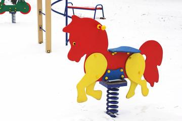 Children's swing. Winter. Playground. Wooden horse