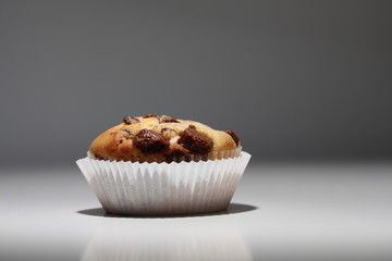 Muffin mit Schokoladenstückchen in weißem Papier Muffinförmchen steht im Spotlight