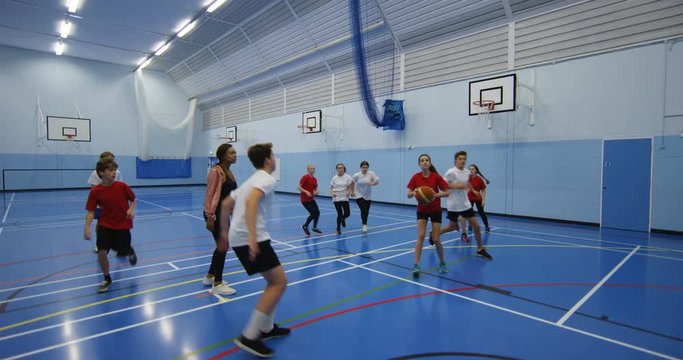 4K Sports teacher coaching male & female pupils during school basketball game