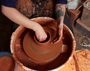 production process of pottery.  Forming a clay mug on a potter's wheel.