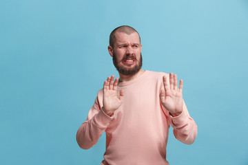 Young man with disgusted expression repulsing something, isolated on the pink