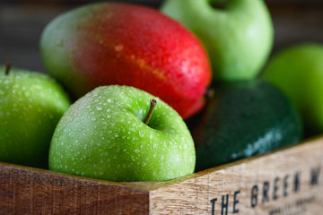 Wet fresh green fruit and vegetables in a wooden box in a kitchen. The concept of organic and healthy food.