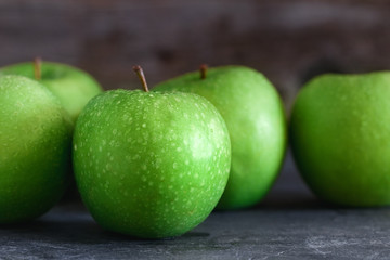 Wet fresh green apples in a row on a table. The concept of organic and healthy food.