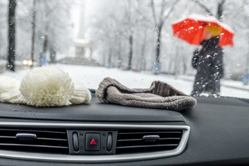 Conceptional winter shot of beanies in a car behind the front window while lady with red umbrella walks by