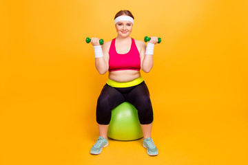 Young woman in exercise clothes with hand weights on exercise balls