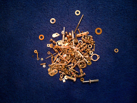 Steel and bronze spare parts on blue background nuts, bolts, and washers
