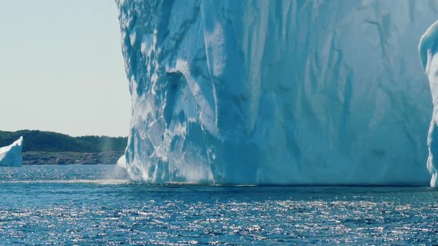 Water falls off massive ice berg floating off the coast in a cold sea