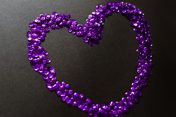 UV paetki scattered in the shape of the heart on a black background.  The decor for the party.