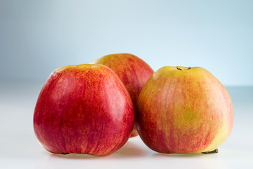 Three red and yellow apples on a neutral background.
