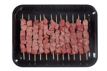 Plastic tray with lamb meat skewers isolated on white background. Top view