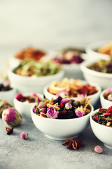 Assortment of dry tea in white bowls. Tea types backgound: green, black, floral, herbal, mint, melissa, ginger, apple, rose, lime tree, fruits, orange, hibiscus, raspberry, cornflower, cranberry