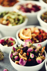 Assortment of dry tea in white bowls. Tea types backgound: green, black, floral, herbal, mint, melissa, ginger, apple, rose, lime tree, fruits, orange, hibiscus, raspberry, cornflower, cranberry
