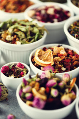 Assortment of dry tea in white bowls. Tea types backgound: green, black, floral, herbal, mint, melissa, ginger, apple, rose, lime tree, fruits, orange, hibiscus, raspberry, cornflower, cranberry