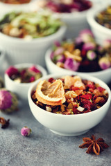Assortment of dry tea in white bowls. Tea types backgound: green, black, floral, herbal, mint, melissa, ginger, apple, rose, lime tree, fruits, orange, hibiscus, raspberry, cornflower, cranberry