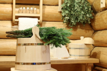 Wooden bucket with fir broom on the background of the log corner of the Russian bath.