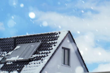house with solar panels on the roof in winter with snowflakes