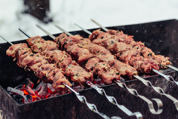Tasty grilled meat on metal skewers on the brazier in winter. Roasted meat cooked at barbecue. BBQ fresh beef meat chop slices. Traditional eastern dish, shish kebab.