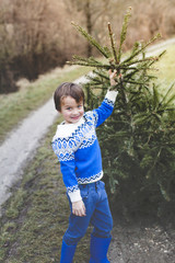 young boy is pulling an old christmas tree for knut